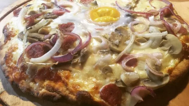 Pizza El Puesto con chorizo Toscano, cebolla, queso champiñones y huevo.